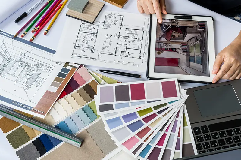 Un designer d'intérieur qui travaille avec ses plans et ses nuanciers d'architecture d'intérieur.